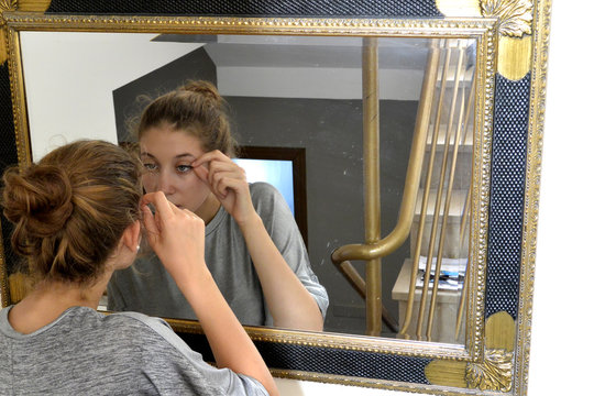 La chica esta arreglandose en frente del espejo