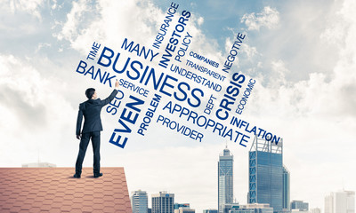 Young businessman standing on house roof and writing leadership 