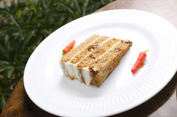 Carrot cake on a white plate decorated with carrots