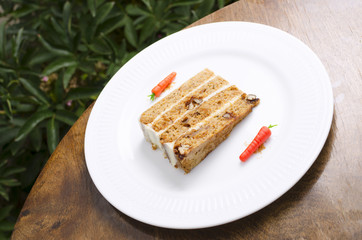 Carrot cake on a white plate decorated with carrots