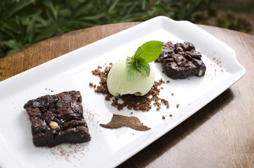 Brownie pie with pistachio ice cream on a white plate