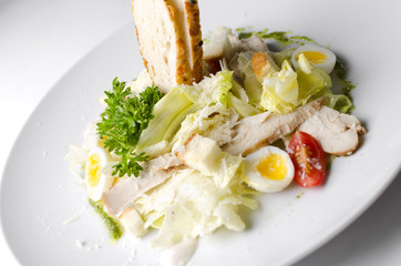 Mix salad with egg quail and croutons on a white plate