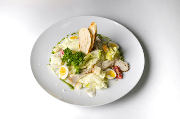 Mix salad with egg quail and croutons on a white plate