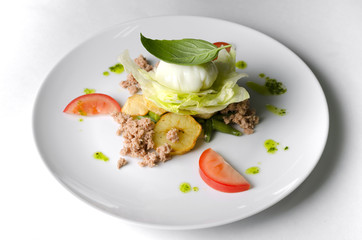 Mix salad with egg poached and tuna on a white plate