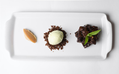 Brownie pie with pistachio ice cream on a white plate