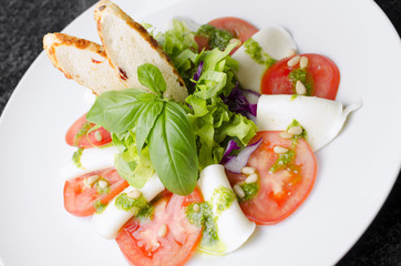 Salad with tomatoes basil and mozzarella with croutons on a white plate