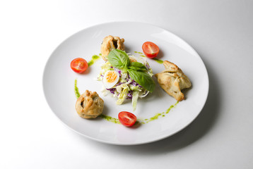 Salad with pies and lettuce leaves on a white plate