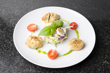 Salad with pies and lettuce leaves on a white plate
