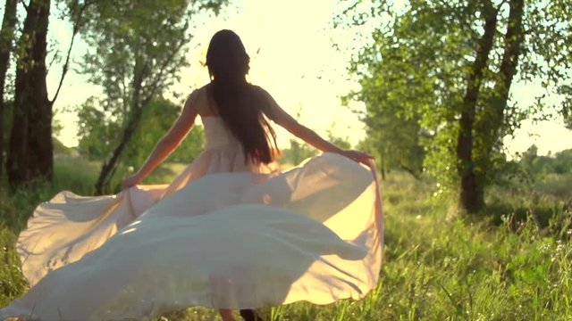 Beauty romantic young woman in long chiffon dress with gown running in the forest on sunset. Slow motion 240 fps. High speed camera 4K UHD