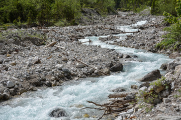A rapid stream coming through a rocky riverbed near the mountains of the Karwendelgebirge