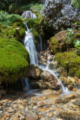 Fototapeta na wymiar Small waterfall coming down through rocks and moss