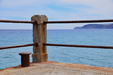 Fototapeta premium Concrete post of rusty ship bollard at the end of a concrete pier overlooking the Atlantic Ocean