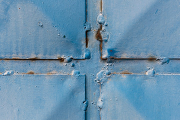 Detail of a blue sheet metal gate with rivets
