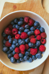 Blueberries and raspberries in white ceramic bowl