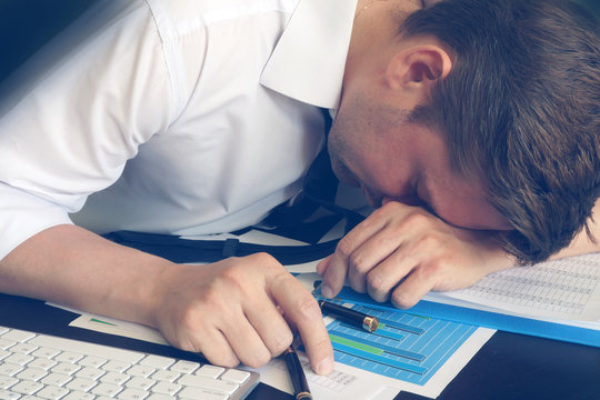 Chronic fatigue syndrome concept. Overworked businessman is sleeping at desk.