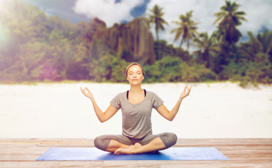 Fototapeta na wymiar woman doing yoga meditation in lotus pose on beach