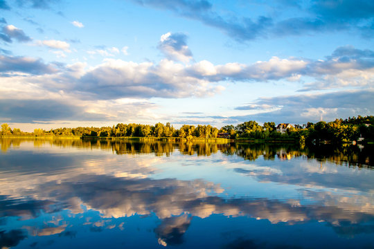 Summer sunset evining sky and clouds reflection in water