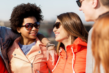 happy teenage friends in shades talking on street