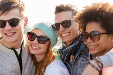 happy teenage friends in shades talking on street