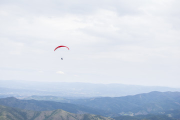 Paragliding in the sky. Paragliders fly over a mountain valley in summer sunny day.