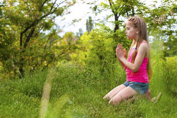 Naklejka na ściany i meble Young girl praying sitting on her knees