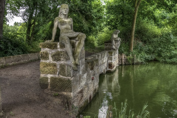 Fototapeta na wymiar Stone bridge by water and statue