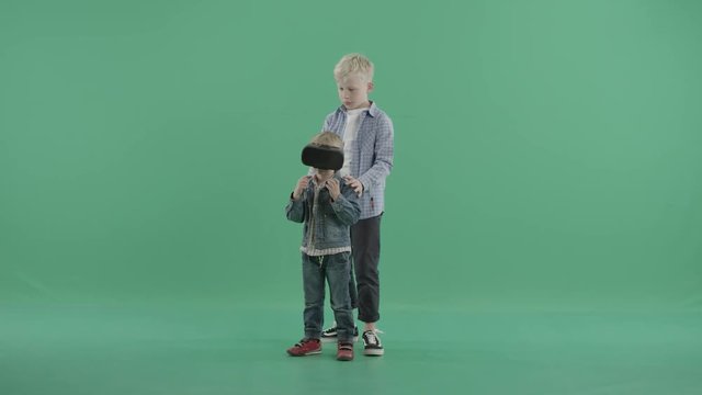 Small boy stands in vr glasses with his older brother