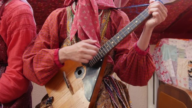 Folk music russian ensemble - woman in Russian folk costume playing the balalaika