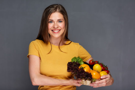 Smiling girl holding basket with summer vegetables.