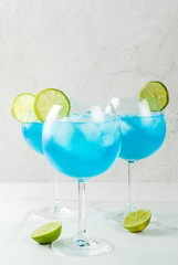 Alcohol drink. Glasses with a blue alcoholic cocktail with ice and lime garnish. Blue Curacao. Liquor. Copy space