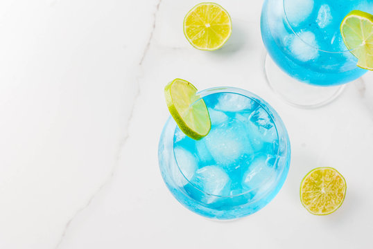 Alcohol drink. Glasses with a blue alcoholic cocktail with ice and lime garnish. Blue Curacao. Liquor. Copy space top view