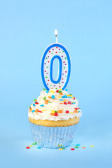 Iced birthday cupcake with with lit number 0 candle and sprinkles