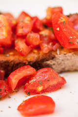 Tasty savory tomato Italian appetizers, or bruschetta, on slices of toasted baguette garnished with basil, close up on a wooden board