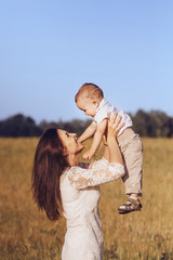 Beautiful mom throws his laughing son in the air. Focus On Foreground.