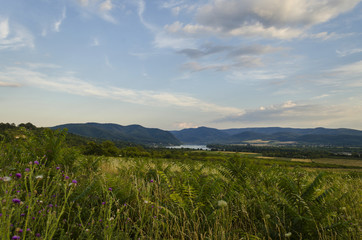 Fototapeta na wymiar river in distance scenic summer green landscape of hills 