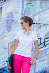 Obraz premium Girl wearing blank white t-shirt, jeans posing against rough street wall