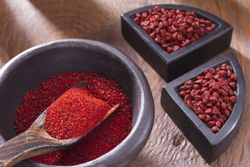 Achiote grains and powder in wooden bowl