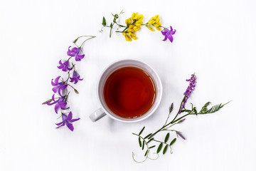 Cup of black tea with wild medicinal flowers on a white background
