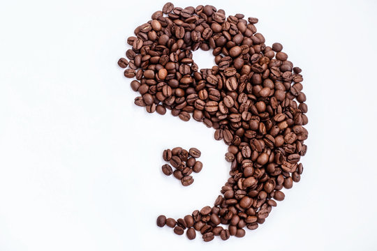 brown coffee beans in the shape of a Yin and Yang on a white background