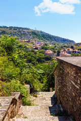 Fototapeta premium Cityscape of balchik town, stone stairs on foreground, houses on green hill, black sea coast in Bulgaria