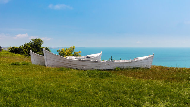 Fototapeta Two white broken old boats on the grass, view from altitude to the sea, black sea coast in Bulgaria