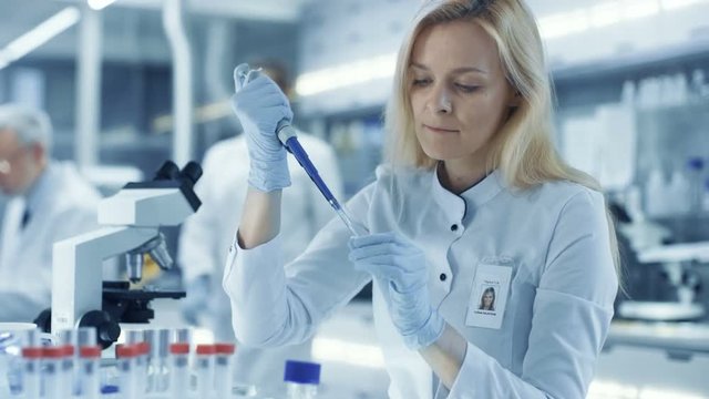 Female Research Scientist Uses Micropipette Filling Test Tubes. Scientist Work in a Big Laboratory/ Research Center. Shot on RED EPIC-W 8K Helium Cinema Camera.