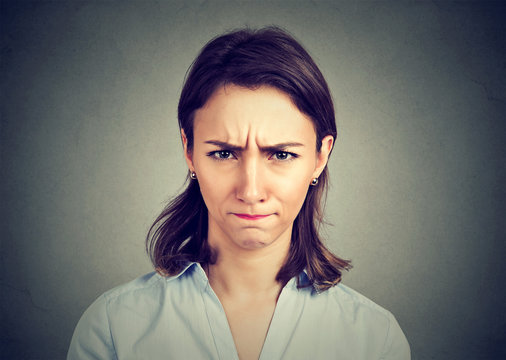 Angry young woman isolated on gray background.