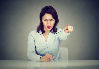 Angry business woman sitting at desk screaming pointing with finger to get out