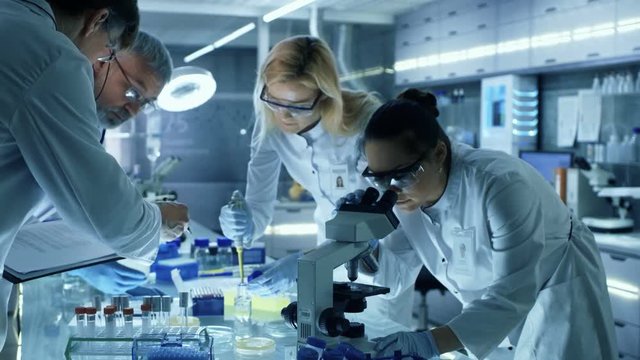 Team of Medical Research Scientists Collectively Working on a New Generation Experimental Drug Treatment. Laboratory Looks Busy, Bright and Modern. Shot on RED EPIC-W 8K Helium Cinema Camera.