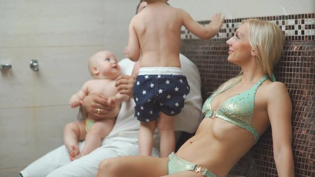 A family of four in hamam, a Turkish steam room. Young parents with two sons in the thermal zone bask in the hamam. A healthy young family with two children in a ham. Thermal center, hammam, spa