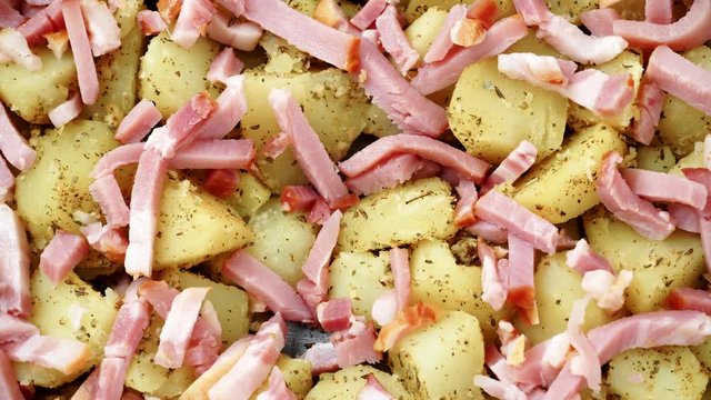 Peeled potatoes with spices, becon meat and onion slices ready to be roasted close up. Food background. Rack focus dolly shot 4K ProRes HQ codec