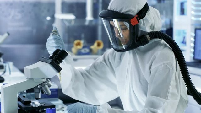 Medical Virology Research Scientist Works in a Hazmat Suit with Mask, She Uses Micropipette. She Works in a Sterile High Tech Laboratory, Research Facility. Shot on RED EPIC-W 8K Helium Cinema Camera.