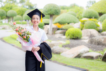 women is a Graduate holding a bouquet and smiling for the camera with happy successful of education