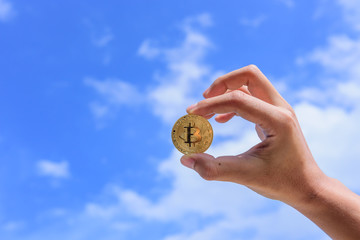 Plakat man's hand holding golden Bitcoin on sky background